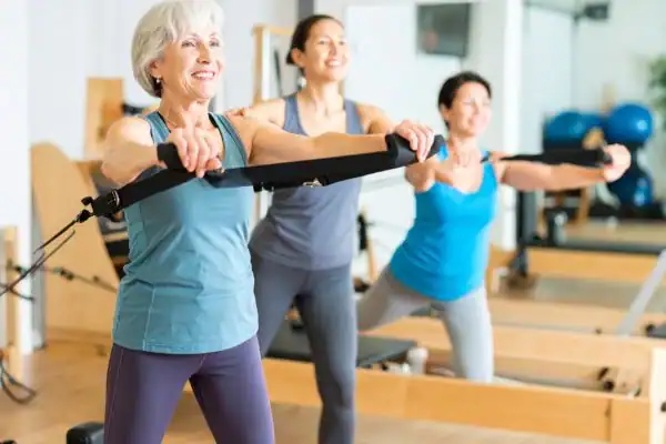 Toning Arms After 60: Empowering Womens Fitness Through Effective Weight Training 2 older woman doing weight training Cumbernauld and resistance in the gym to tone upper arms