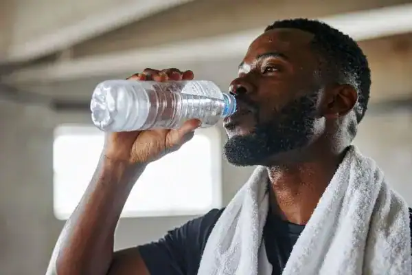Image of man drinking water to improve hydration Cumbernauld  after work out.